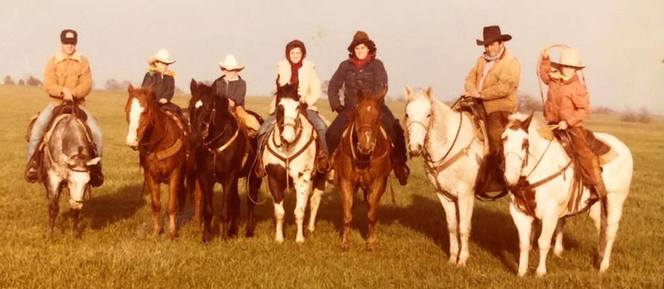 Home photo of a family of cowboys and cowgirls sitting horseback.